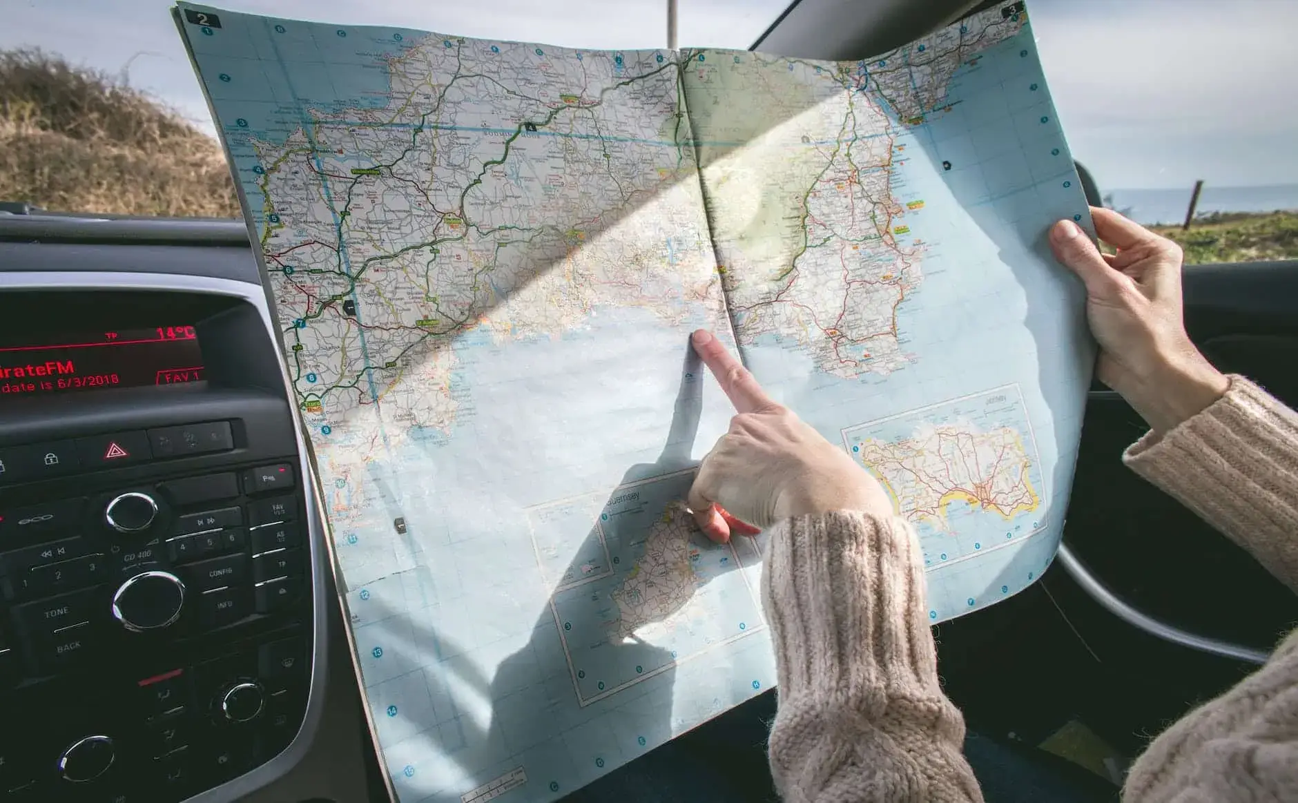 pexels photo 1252500 person wearing beige sweater holding map inside vehicle