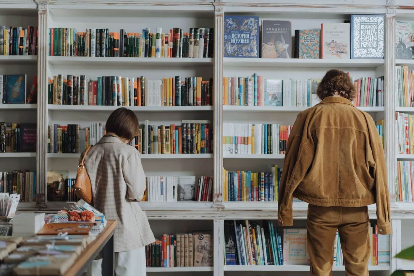 pexels photo 4861300 woman in brown coat standing in front of books