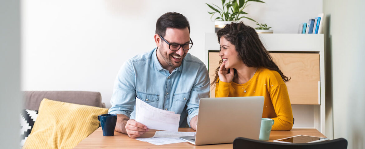 Marrige Shared Finances smiling couple managing finances, reviewing their bank accounts using laptop computer and calculator at modern kitchen stock photo